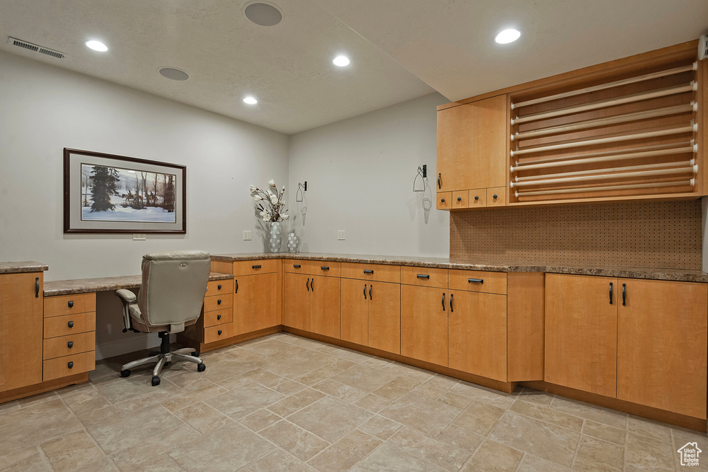 Unfurnished office featuring recessed lighting, light stone finish floors, and built in study area