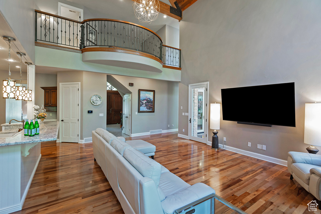 Living area featuring a chandelier, a towering ceiling, wood finished floors, and baseboards