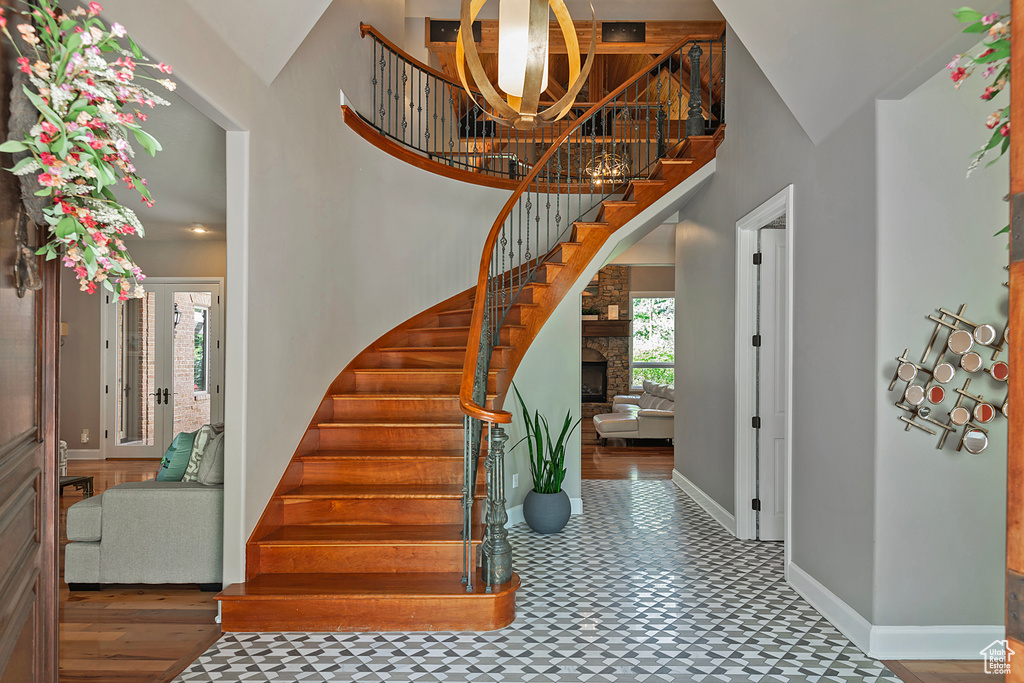 Foyer entrance featuring stairway, a high ceiling, baseboards, tile patterned floors, and a fireplace