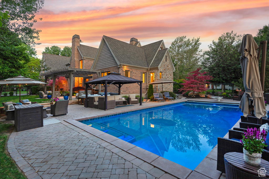 Swimming pool featuring outdoor lounge area, a gazebo, a patio area, and a diving board