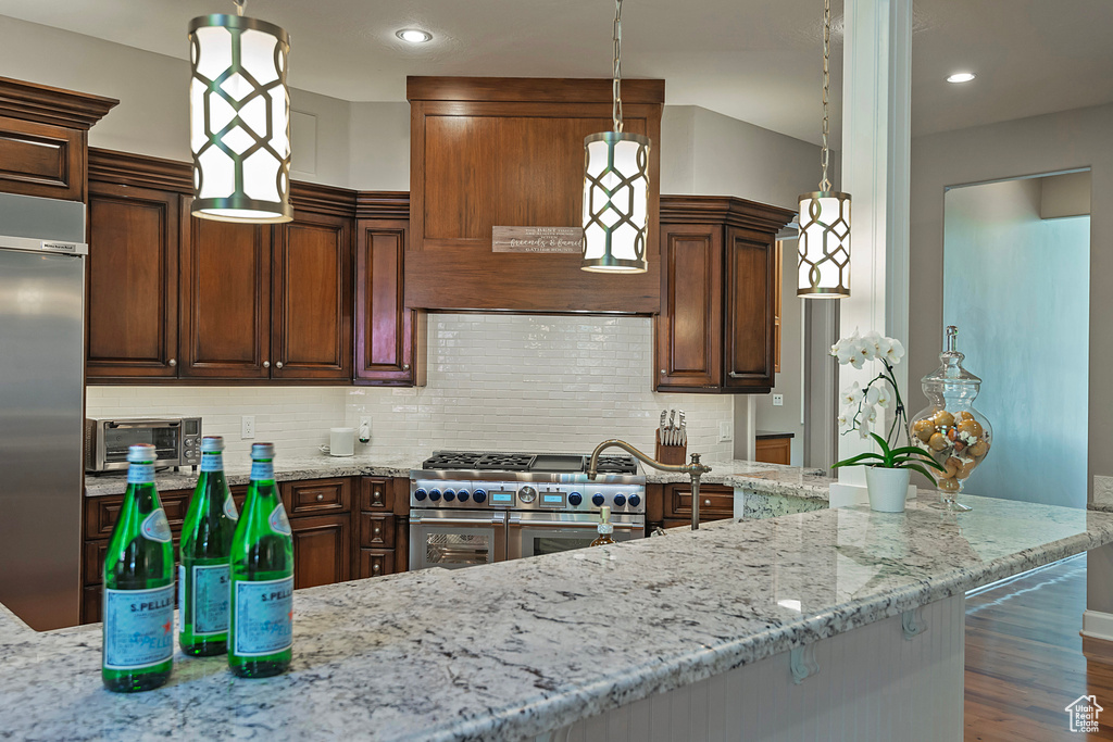 Kitchen featuring high end appliances, light stone counters, decorative backsplash, and recessed lighting