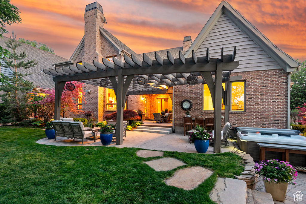 Back of house at dusk with brick siding, a pergola, a chimney, and a patio