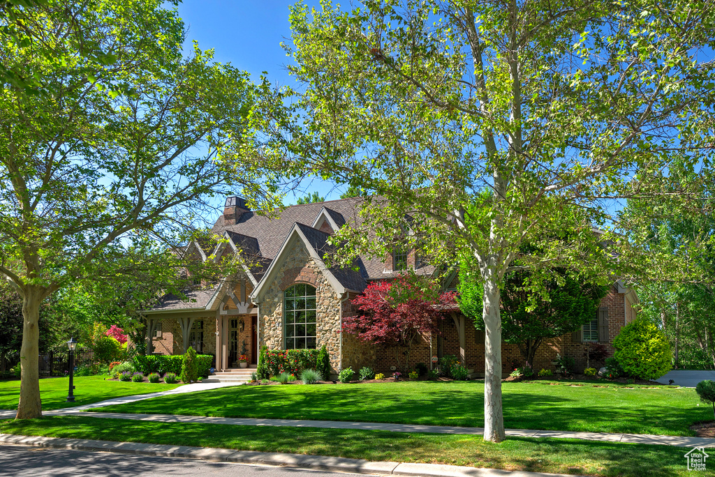 View of front of property featuring stone siding, a front lawn, and a chimney