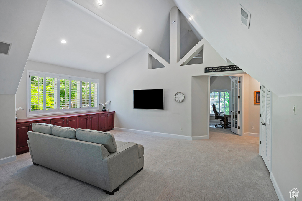 Living room with light carpet, baseboards, recessed lighting, and high vaulted ceiling