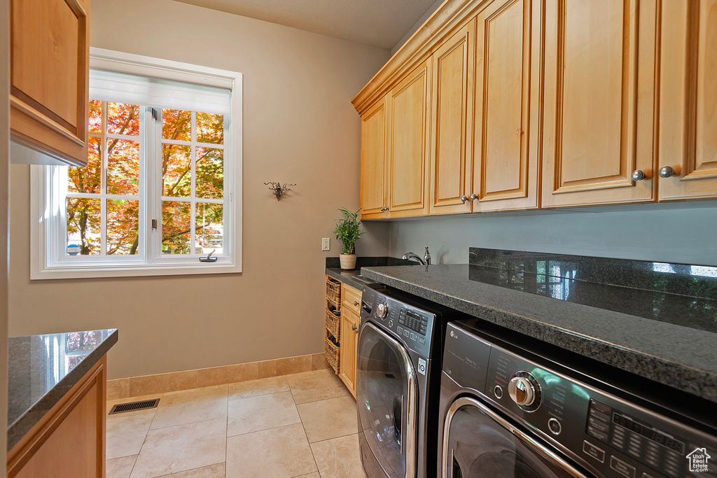 Laundry room featuring independent washer and dryer, baseboards, cabinet space, and light tile patterned floors