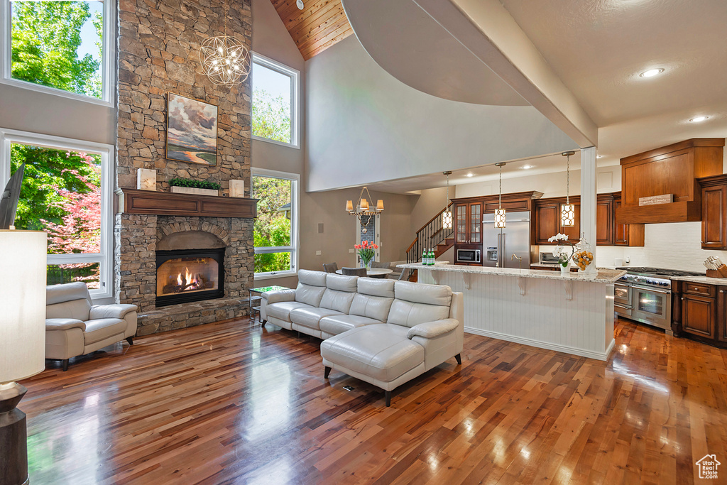 Living room with hardwood / wood-style floors, a chandelier, a fireplace, high vaulted ceiling, and recessed lighting