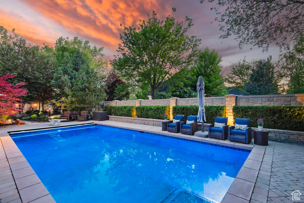 Pool at dusk featuring a patio area