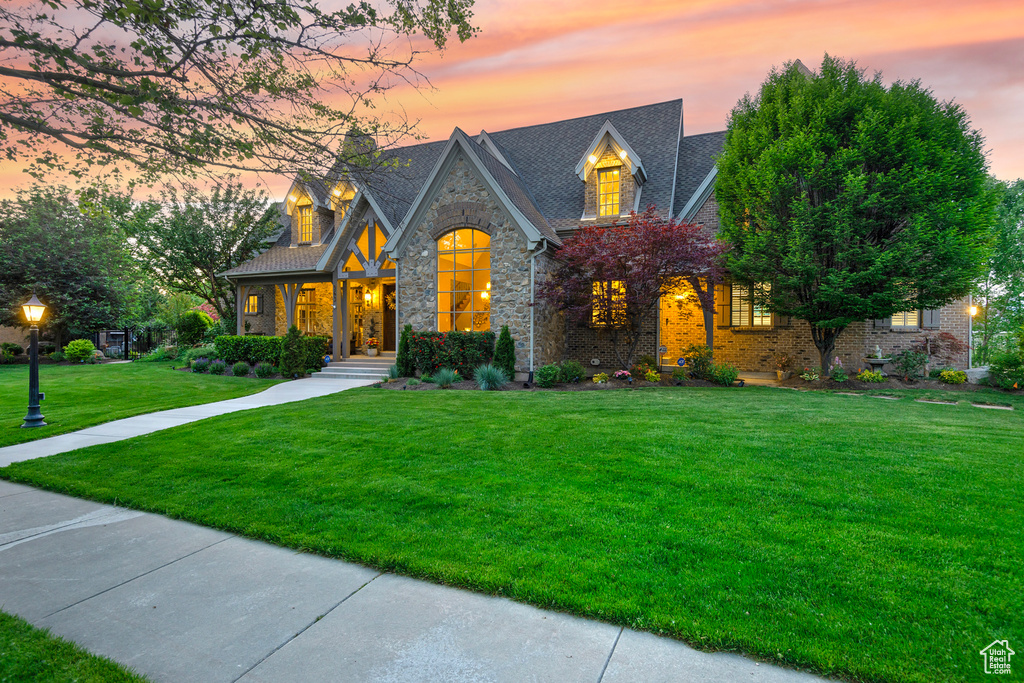 View of front of home featuring stone siding and a lawn