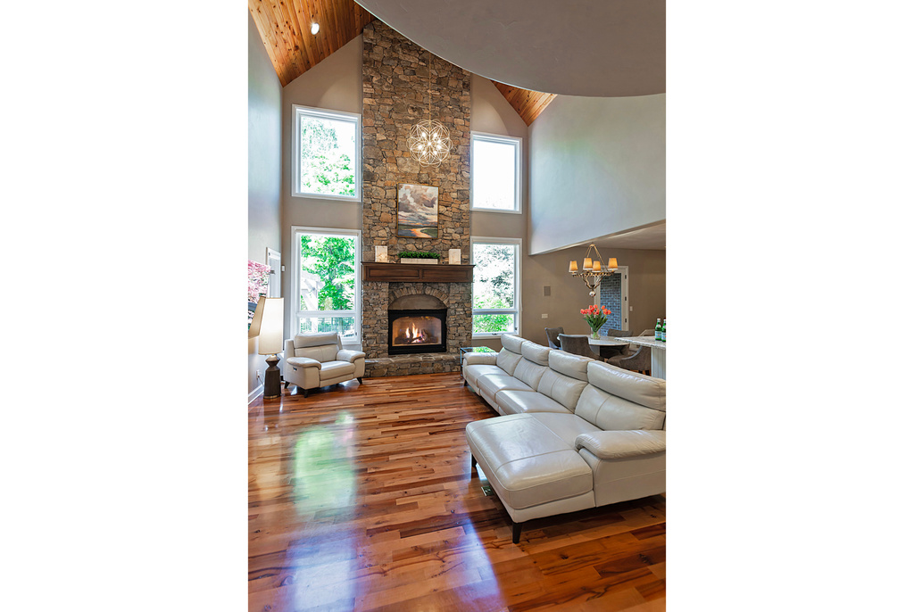 Living room with high vaulted ceiling, a fireplace, a chandelier, and wood finished floors