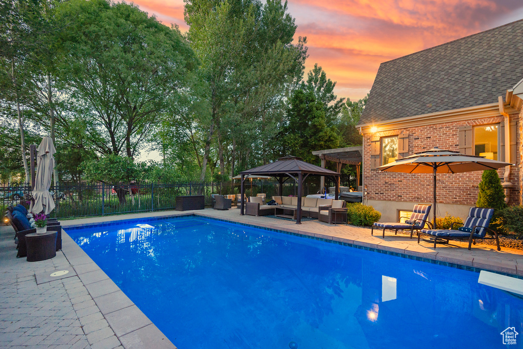 View of swimming pool with outdoor lounge area, a gazebo, a patio, and a diving board