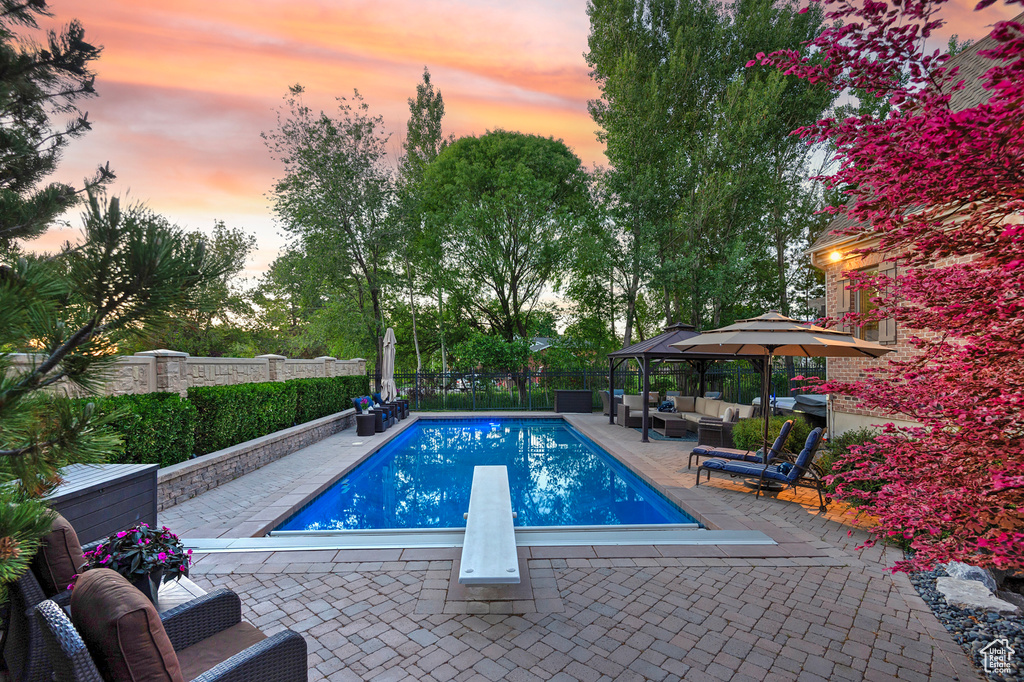 View of swimming pool with an outdoor hangout area, a patio, a diving board, and a fenced backyard