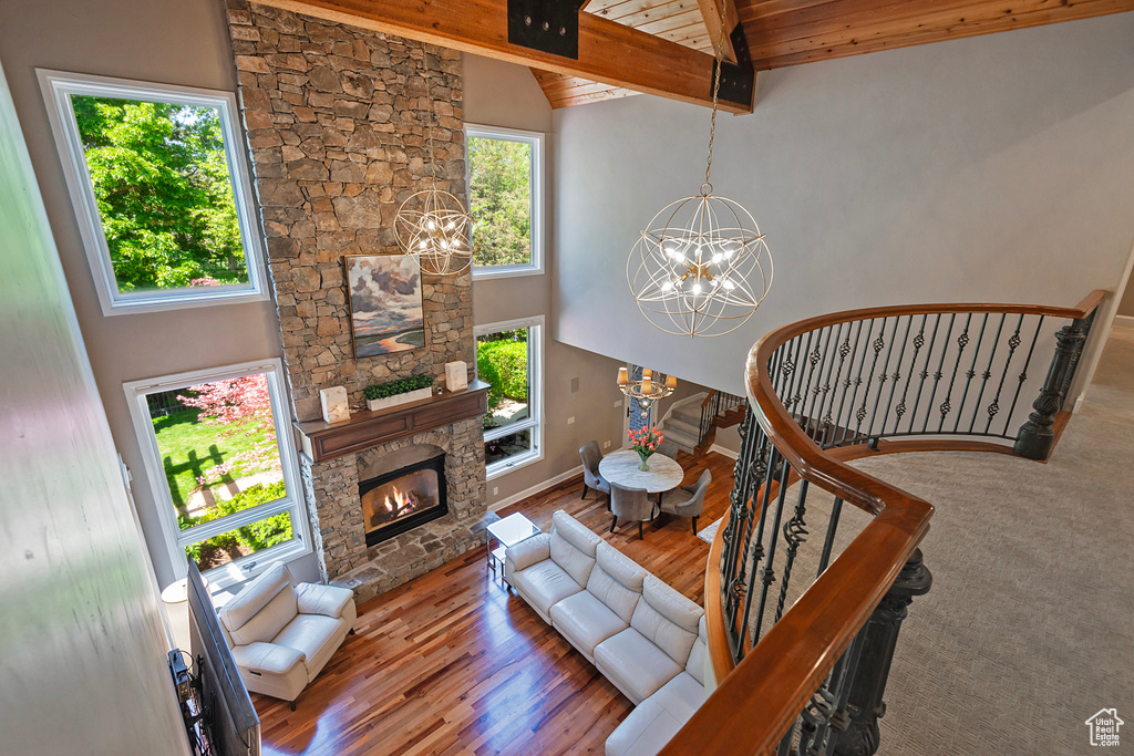 Living area featuring a chandelier, plenty of natural light, a fireplace, wood finished floors, and high vaulted ceiling