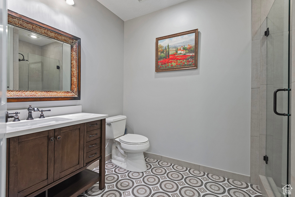 Full bath with toilet, vanity, a shower stall, baseboards, and tile patterned floors