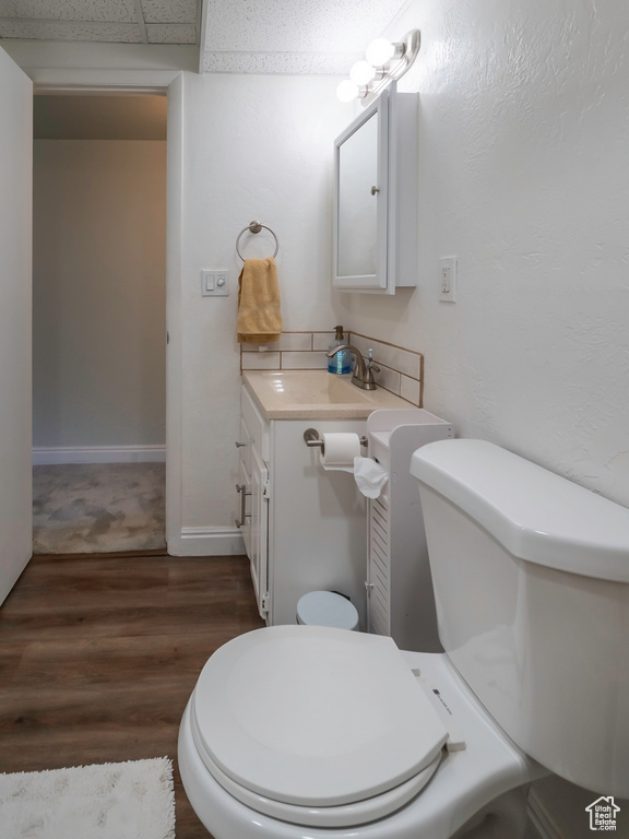 Bathroom with vanity, wood finished floors, toilet, and baseboards