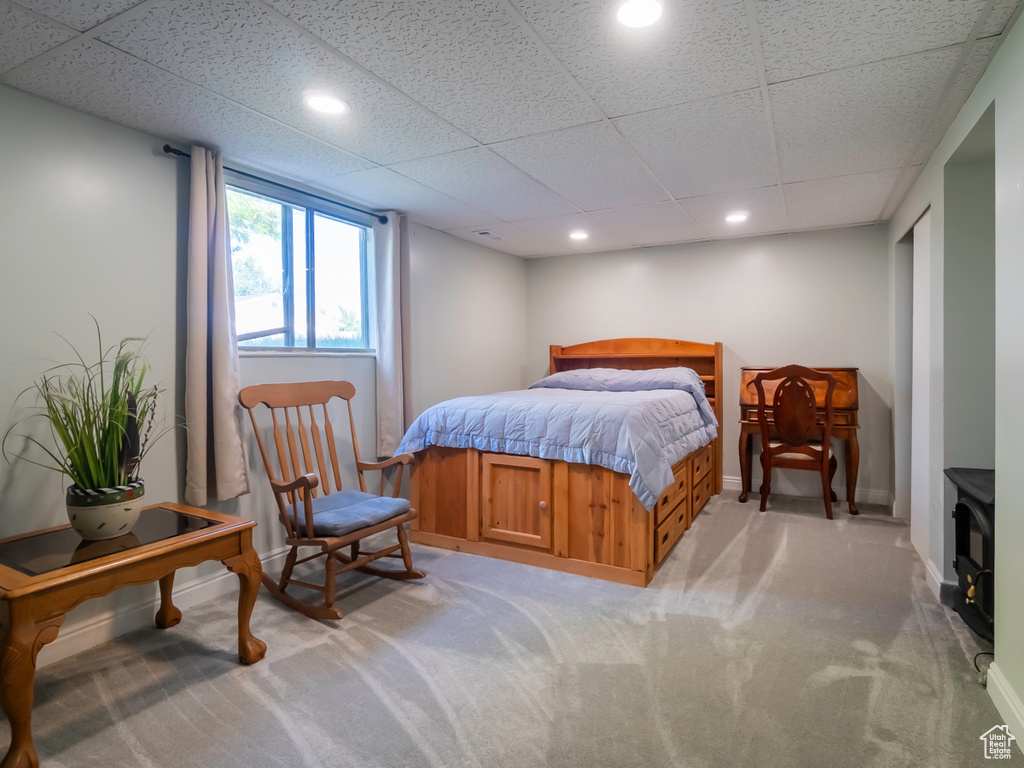 Bedroom with light colored carpet, a paneled ceiling, recessed lighting, baseboards, and a wood stove