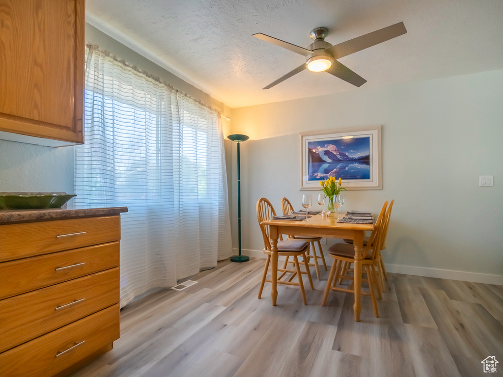 Dining space with light wood-type flooring, baseboards, and a ceiling fan