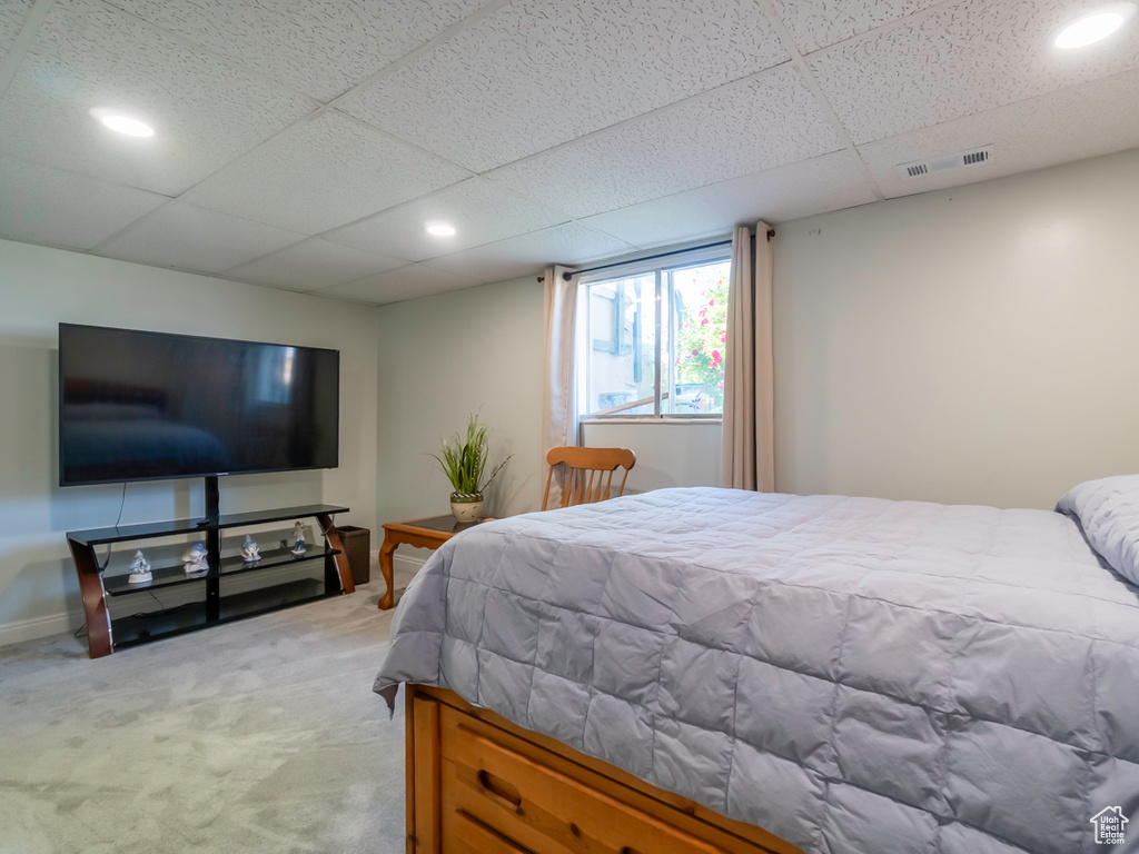 Bedroom with light carpet, a drop ceiling, and recessed lighting