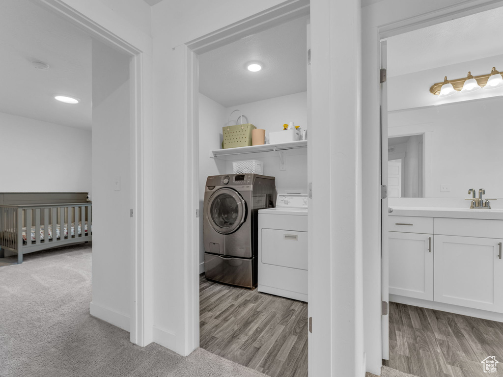 Laundry area with independent washer and dryer and light wood finished floors