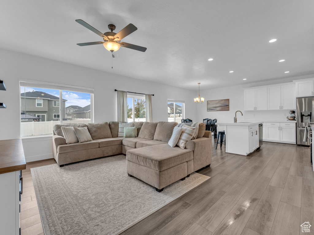 Living area featuring healthy amount of natural light, recessed lighting, light wood-style flooring, ceiling fan, and a chandelier