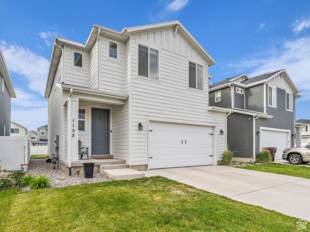 Traditional-style house with an attached garage, a front lawn, board and batten siding, and driveway