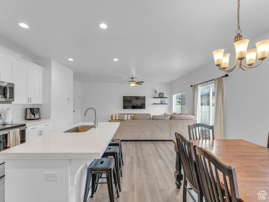 Kitchen with a sink, stainless steel appliances, light wood finished floors, recessed lighting, and a kitchen island with sink