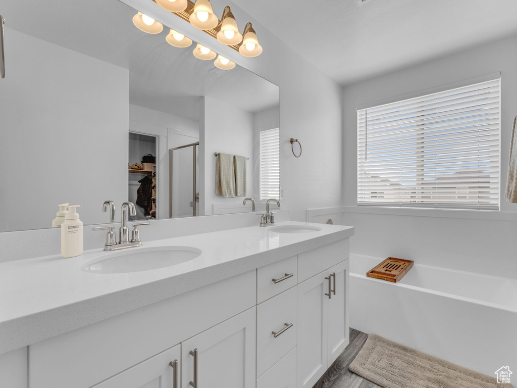 Full bath with double vanity, a bath, a spacious closet, and a stall shower
