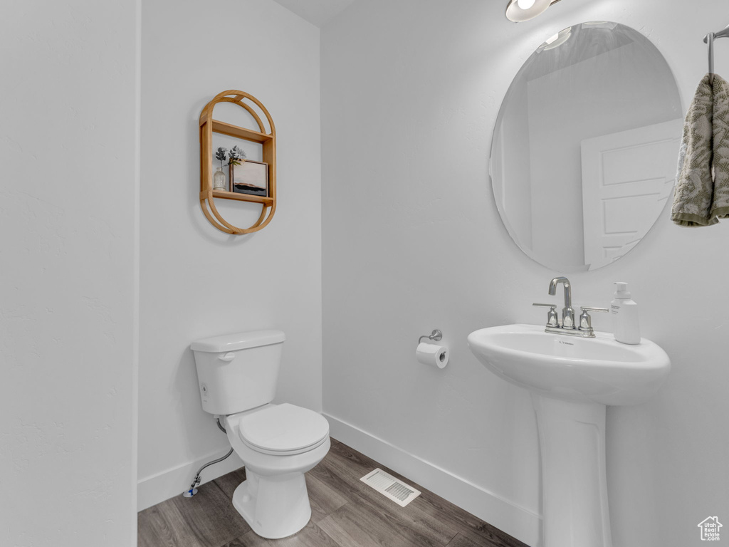 Half bath with toilet, wood finished floors, and baseboards