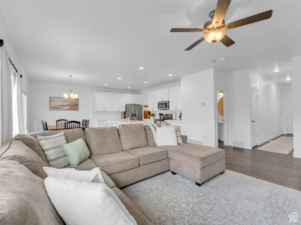 Living area with a chandelier, a ceiling fan, wood finished floors, recessed lighting, and baseboards