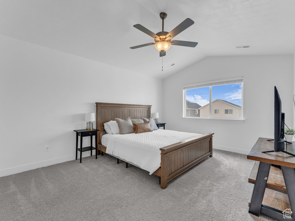 Carpeted bedroom with vaulted ceiling, baseboards, and ceiling fan