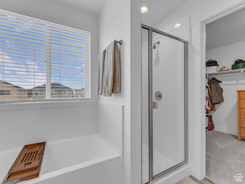 Full bath with a stall shower, a bath, a walk in closet, and baseboards