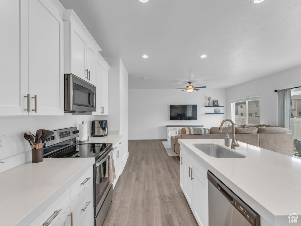 Kitchen with appliances with stainless steel finishes, a sink, open floor plan, ceiling fan, and recessed lighting