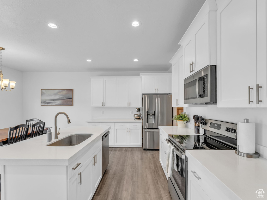 Kitchen featuring stainless steel appliances, a sink, recessed lighting, light countertops, and light wood finished floors