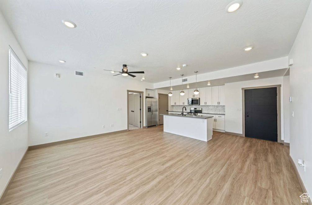 Kitchen with appliances with stainless steel finishes, open floor plan, a sink, recessed lighting, and an island with sink