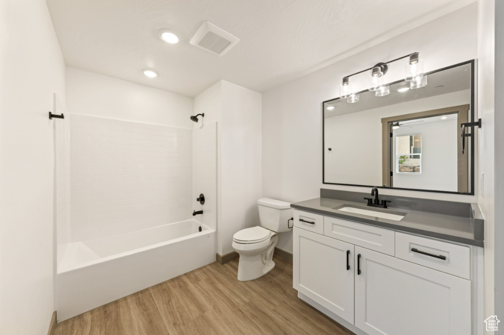 Full bath featuring wood finished floors, toilet, vanity, and shower / bath combination