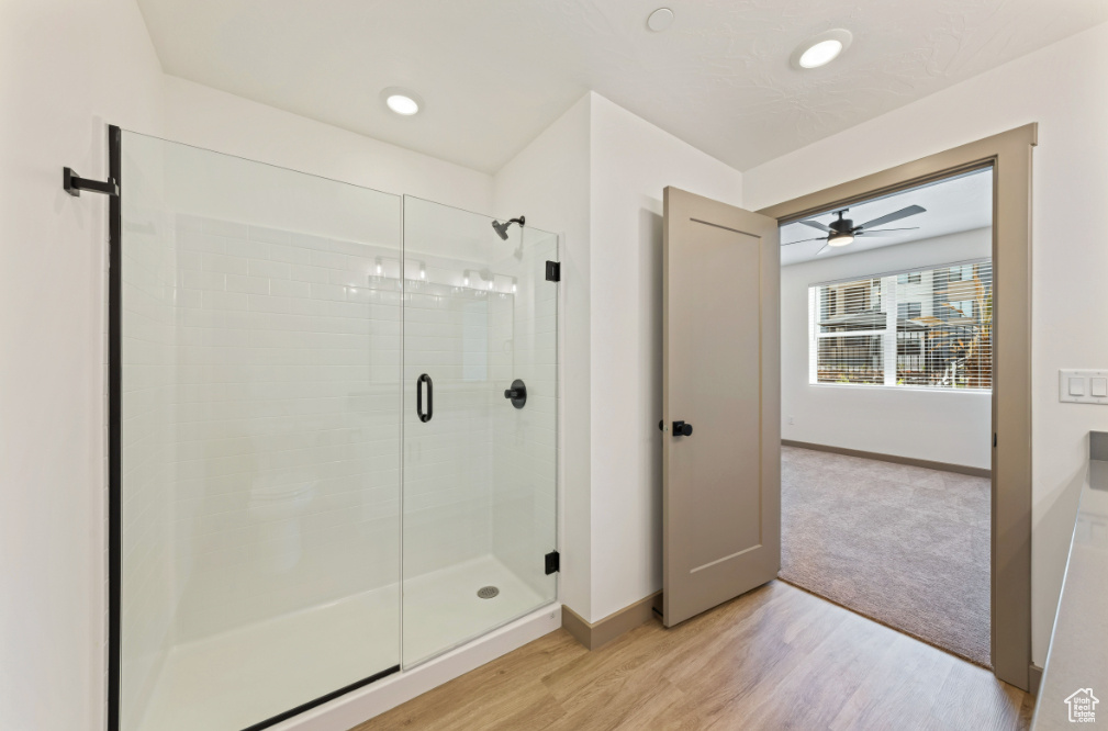 Bathroom with a shower stall, baseboards, wood finished floors, and ceiling fan