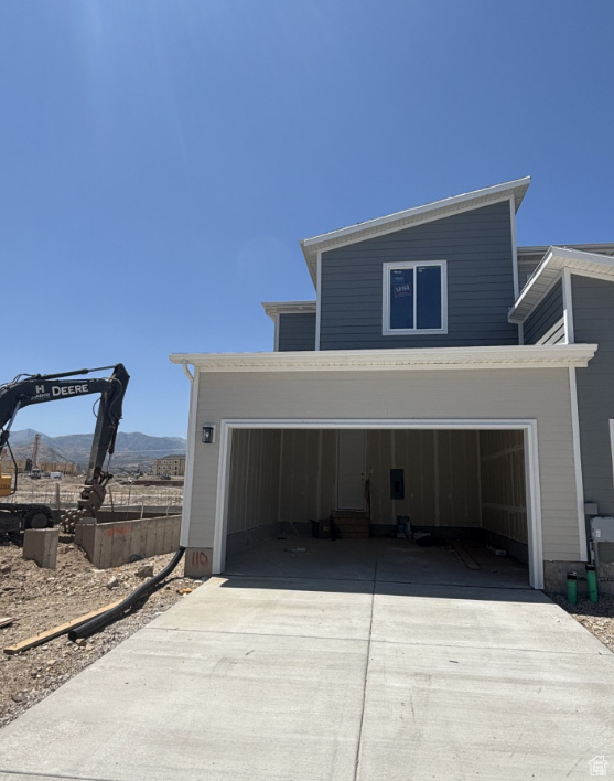 View of side of home with concrete driveway, a mountain view, and an attached garage