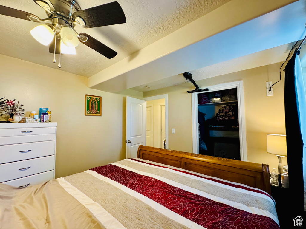 Bedroom with a textured ceiling and a ceiling fan