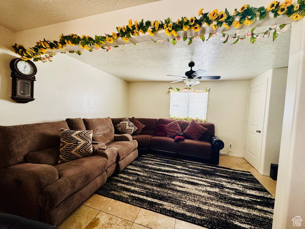 Living area with light tile patterned floors, a textured ceiling, and a ceiling fan