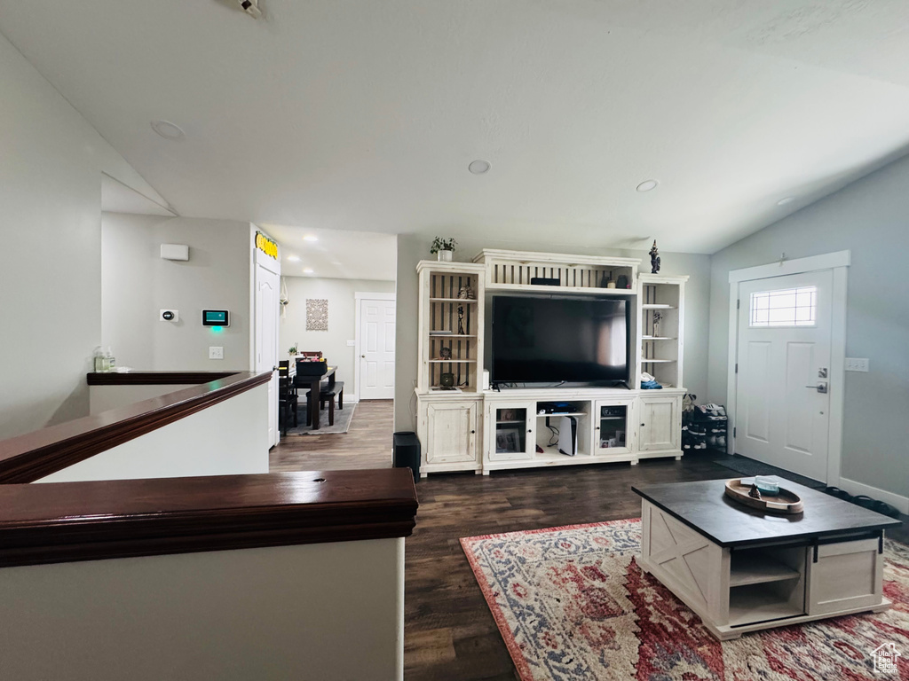 Living area with dark wood-type flooring, lofted ceiling, baseboards, and recessed lighting