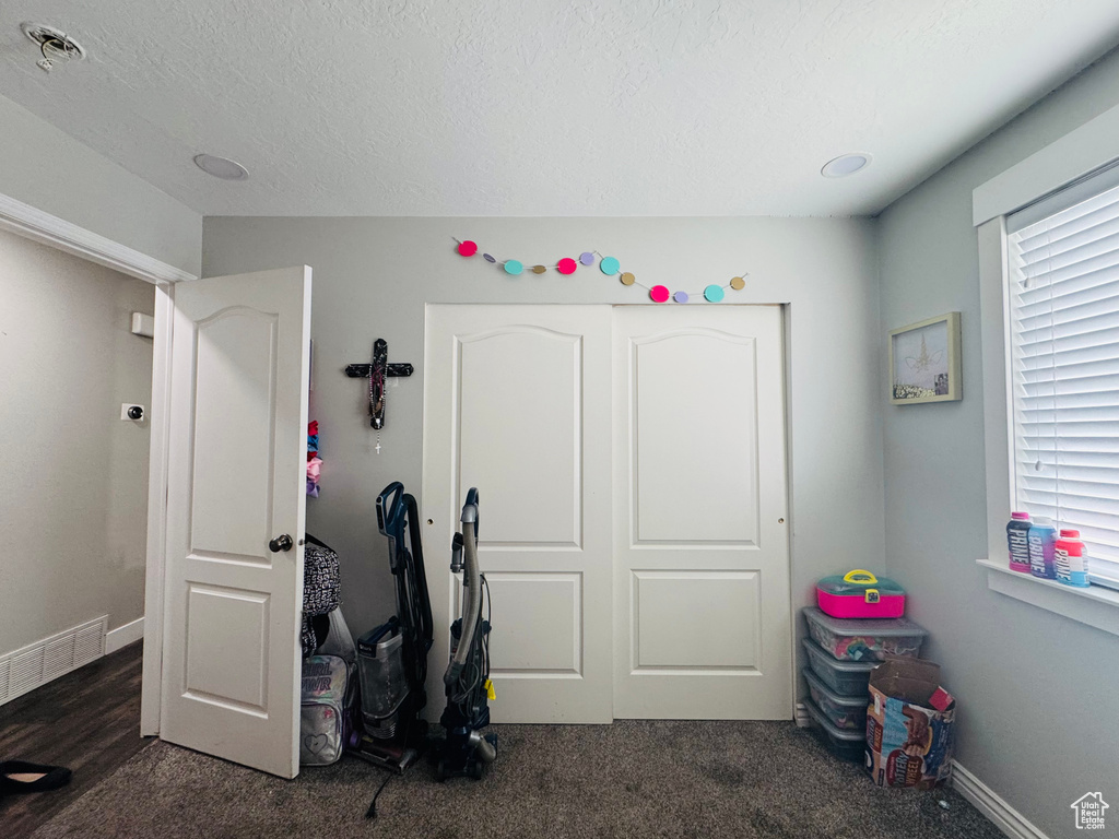 Carpeted bedroom with multiple windows, a textured ceiling, and baseboards