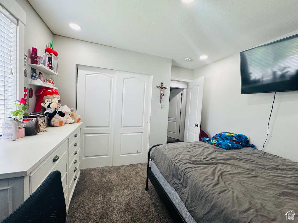 Bedroom with dark colored carpet, recessed lighting, and a closet