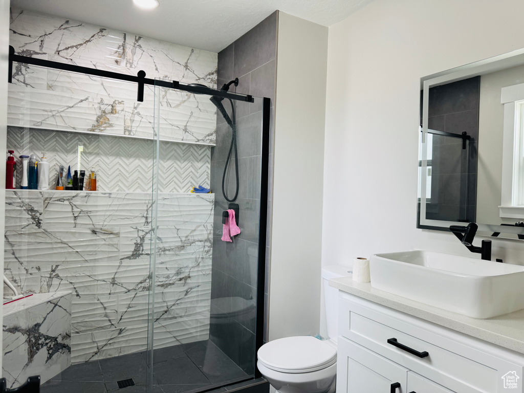 Bathroom with vanity, toilet, and a marble finish shower