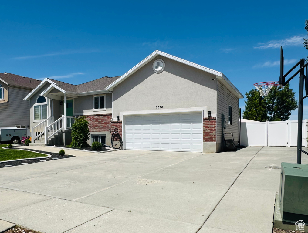 View of front of house with a garage, brick siding, concrete driveway, and stucco siding