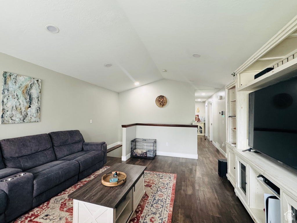 Living area featuring lofted ceiling, dark wood-type flooring, baseboards, and recessed lighting