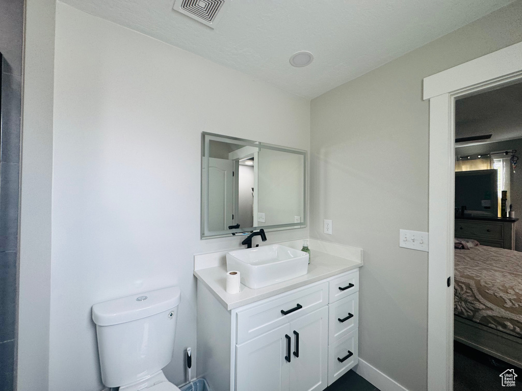 Bathroom featuring vanity, connected bathroom, toilet, and baseboards