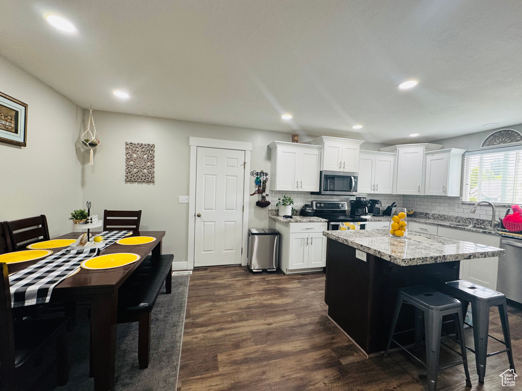 Kitchen featuring appliances with stainless steel finishes, a sink, tasteful backsplash, white cabinetry, and recessed lighting