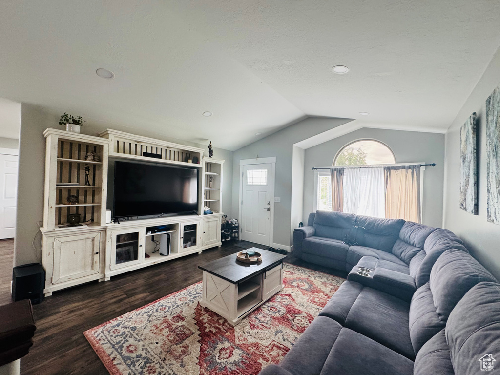 Living room featuring dark wood-type flooring, lofted ceiling, recessed lighting, and baseboards