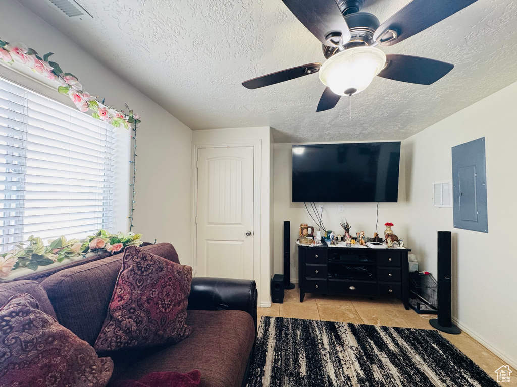 Living room with electric panel, a textured ceiling, ceiling fan, and light tile patterned floors