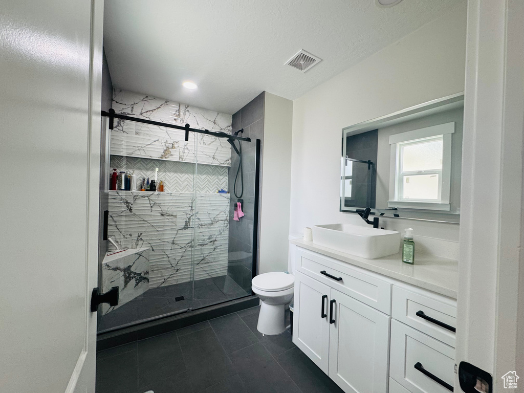 Full bath featuring vanity, toilet, a stall shower, and tile patterned flooring