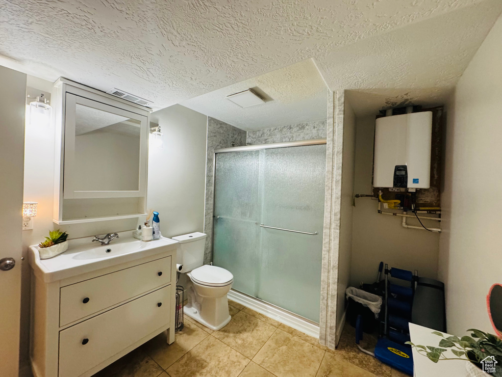 Full bath with tankless water heater, toilet, a shower stall, tile patterned flooring, and vanity